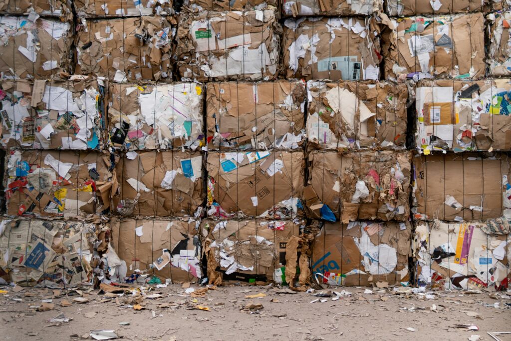Large bales of recycled cardboard stacked outdoors, ready for processing.