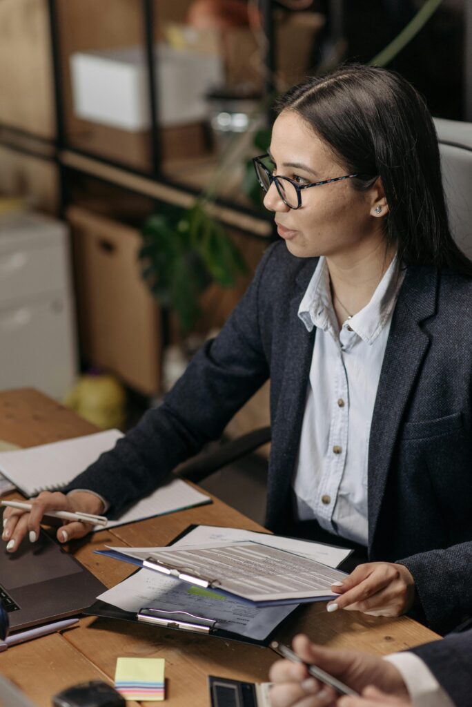 pexels photo 7654449 7654449 Asian woman in blazer working with documents at office desk. Ideal for business and work themes.